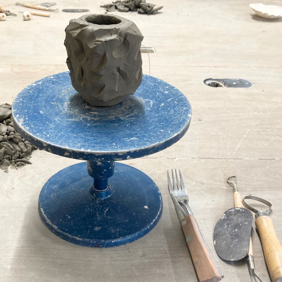 carved clay pot on blue stand