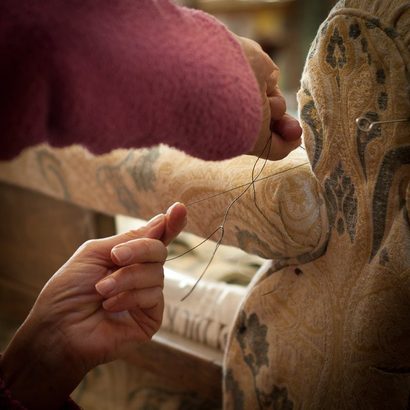 Hands sewing a patterned fabric chair